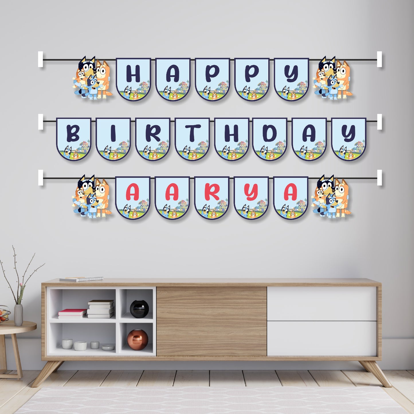 Bluey theme name bunting hung across a birthday party cake table as wall decoration, featuring Bluey and Bingo character flags spelling child's name – BluParty