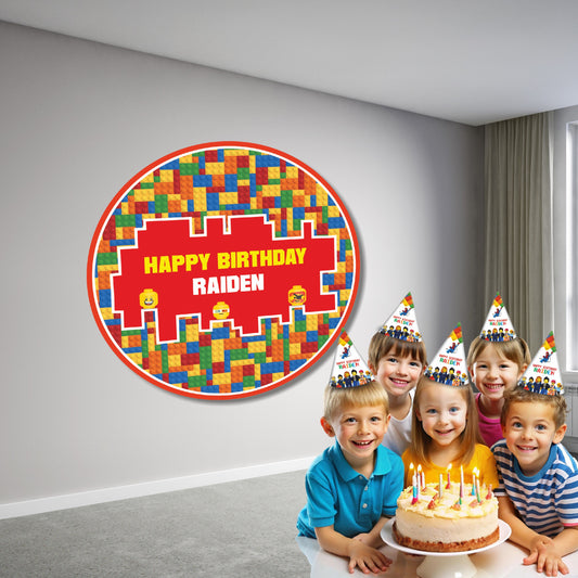 LEGO themed round birthday backdrop displayed behind a cake table with balloon garland in red yellow and blue, personalized party decoration setup for kids
